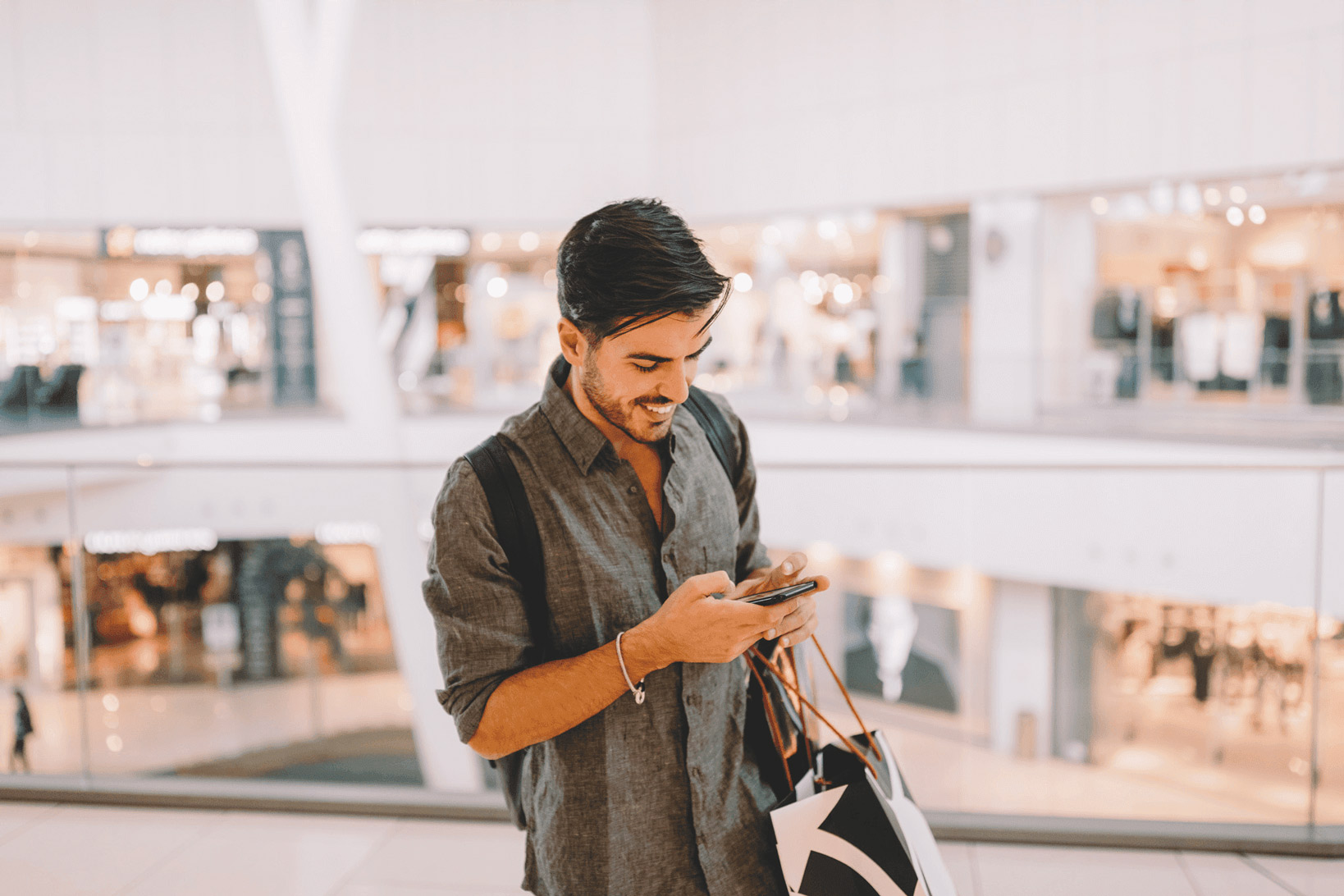 Homme souriant ayant terminé son shopping qui utilise son téléphone pour faire de la détaxe